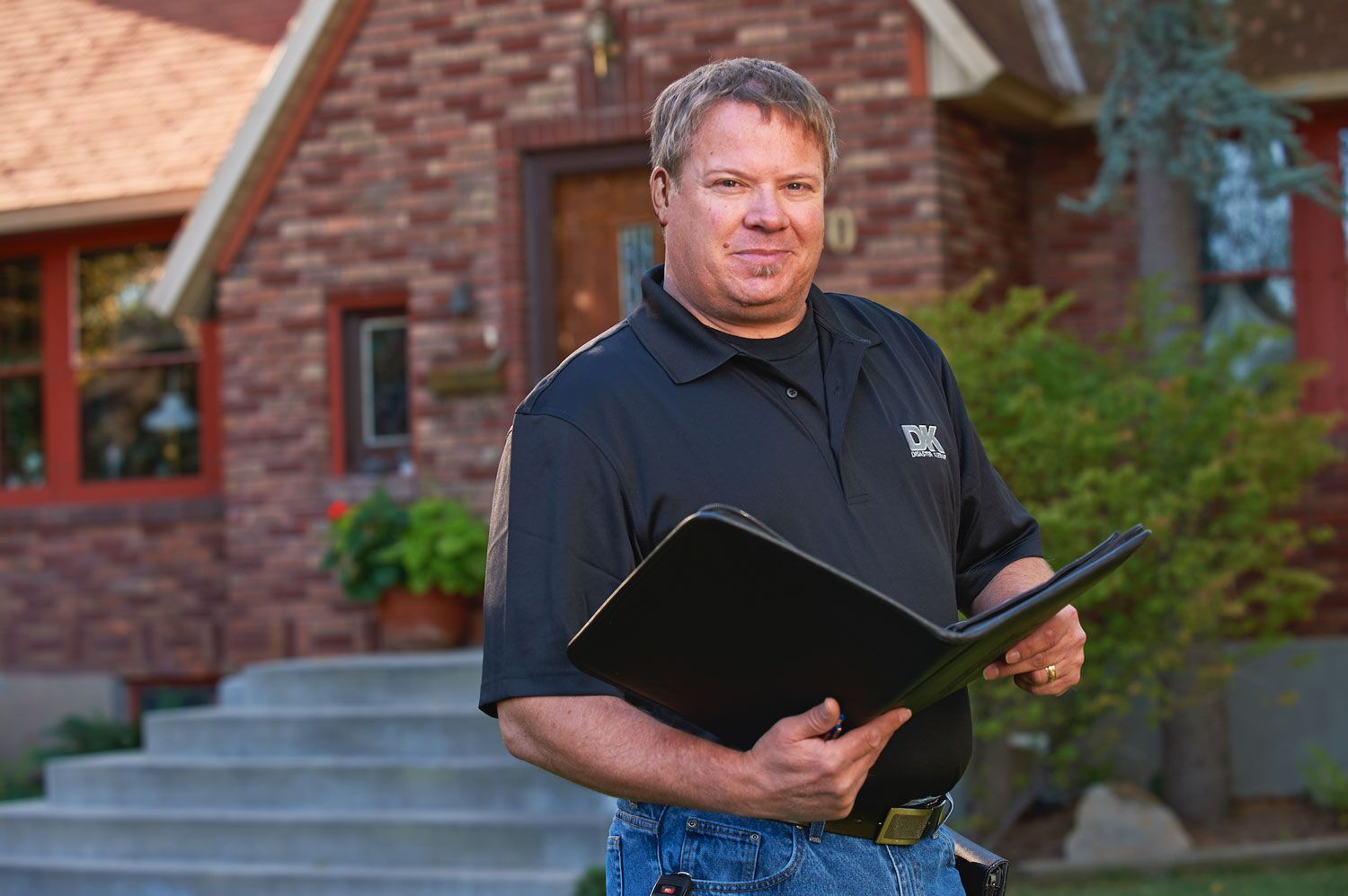 A middle-aged male holding a portfolio looking at the camera
