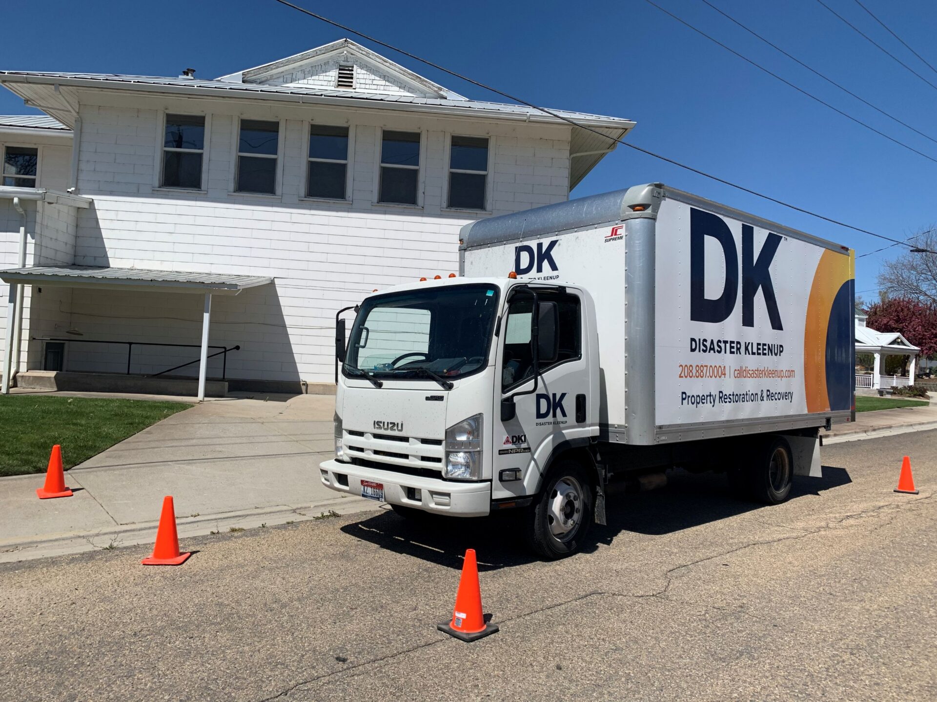 A Distaster kleenup truck parked outside of a residence 